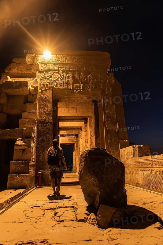 A young man visiting the illuminated Kom Ombo Temple at night