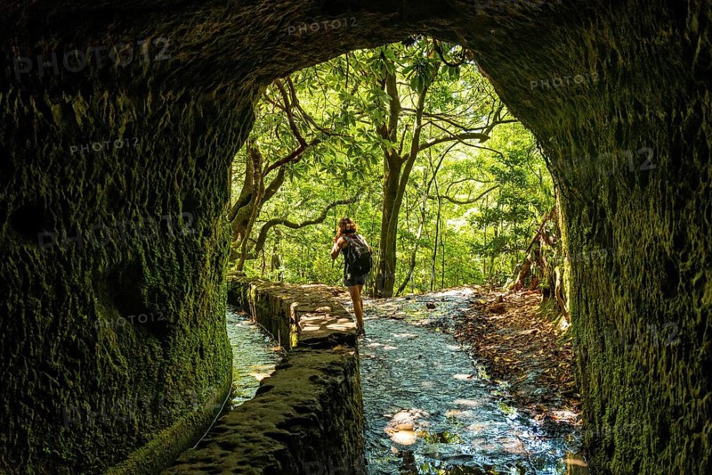 A young woman trekking in the cave at Levada do Caldeirao Verde
