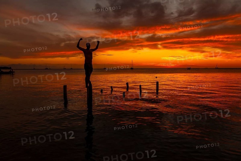 A young man in the water at the Orange Sunset on the West End beach of Roatan. Honduras