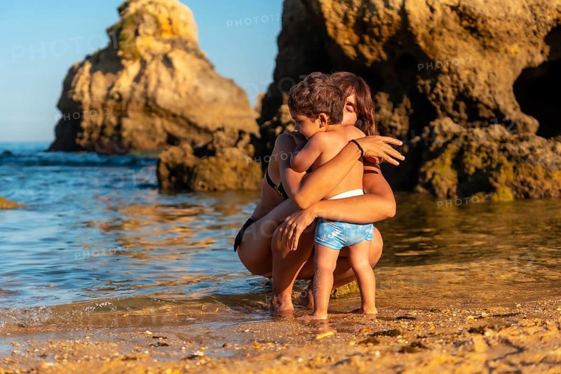 A mother hugging her son on the beach at Praia dos Arrifes