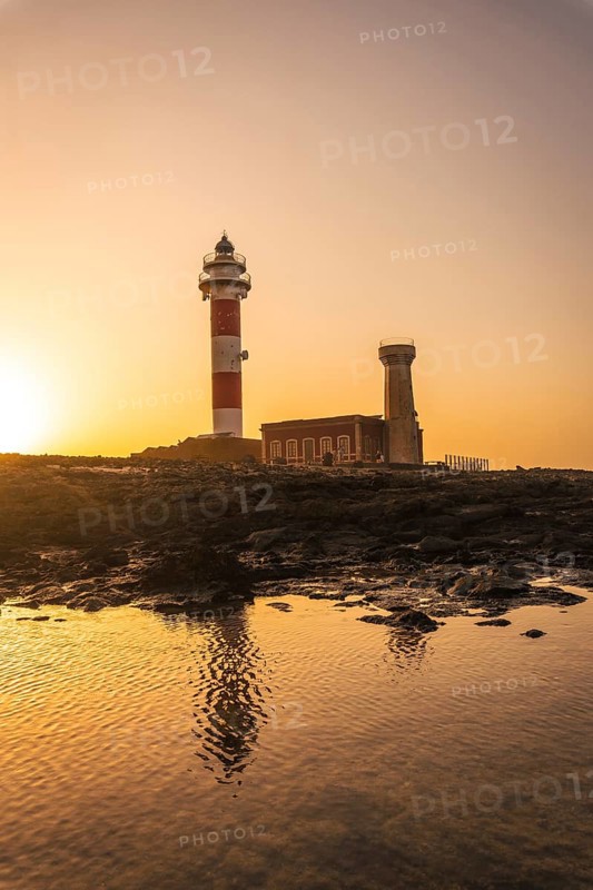 Sunset at the Toston Lighthouse near the sea with the reflected lighthouse