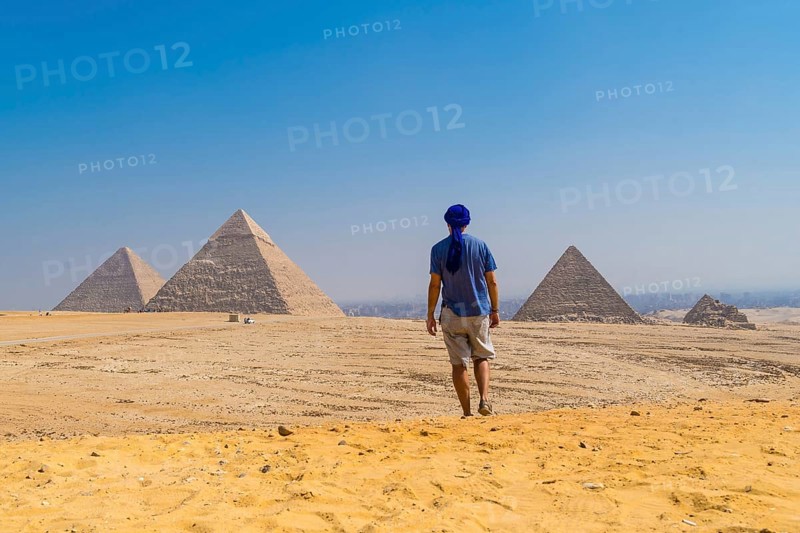 A young man in a blue turban walking next to the Pyramids of Giza