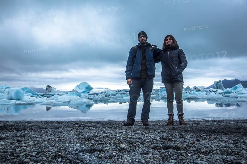 A couple with a backpack looking at the Jokulsarlon Ice Lake in the golden circle of southern Iceland