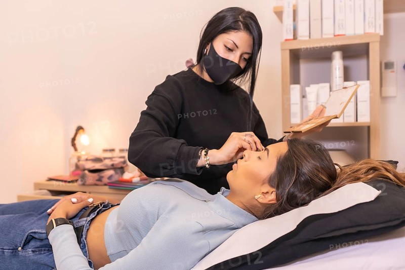 Professional makeup artist attending a client lying on stretcher on a salon