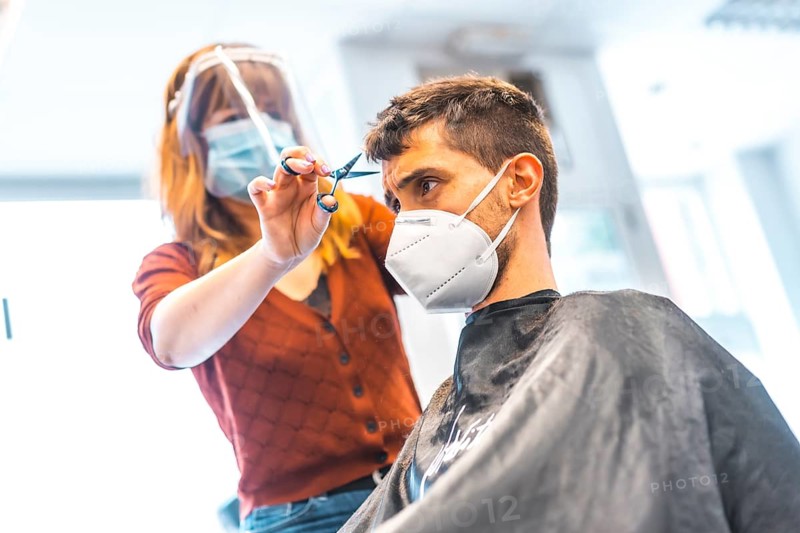 Hairdressers after the Coronavirus pandemic. Hairdresser with face mask and protective screen