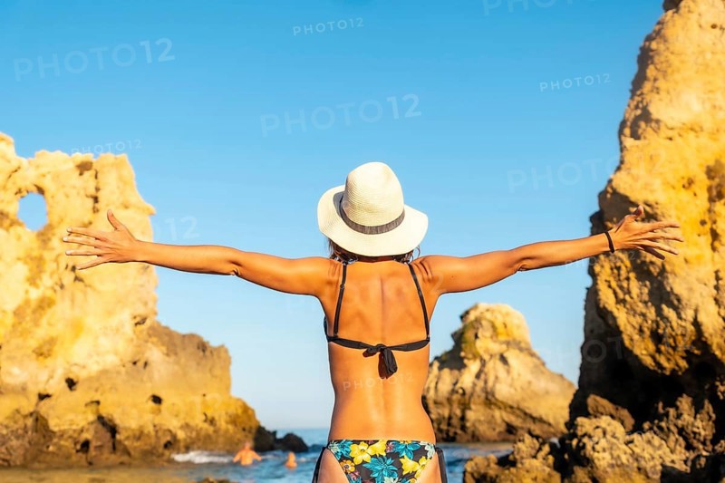 A woman with a hat on vacation at Praia dos Arrifes