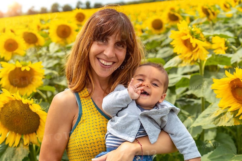 Portrait of a Caucasian mother and her baby laughing in a sunflower setting