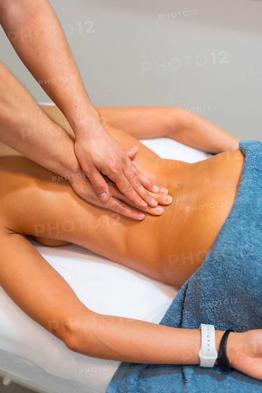 Physiotherapeutic massage to an unrecognizable woman lying on a stretcher on her back