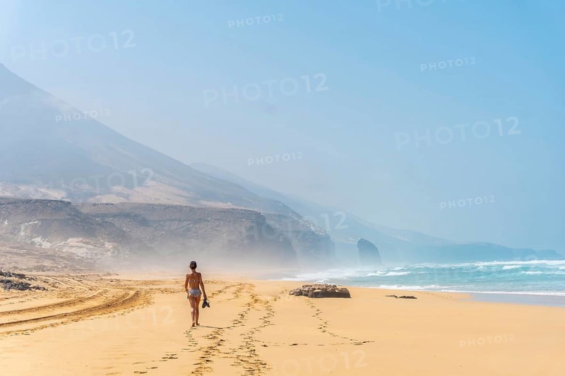 A young woman on the wild beach Cofete of the natural park of Jandia