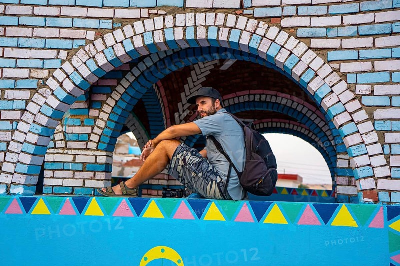A young tourist sitting on a beautiful terrace of a traditional blue house in a Nubian village along the Nile river and near the city of Aswan. Egypt