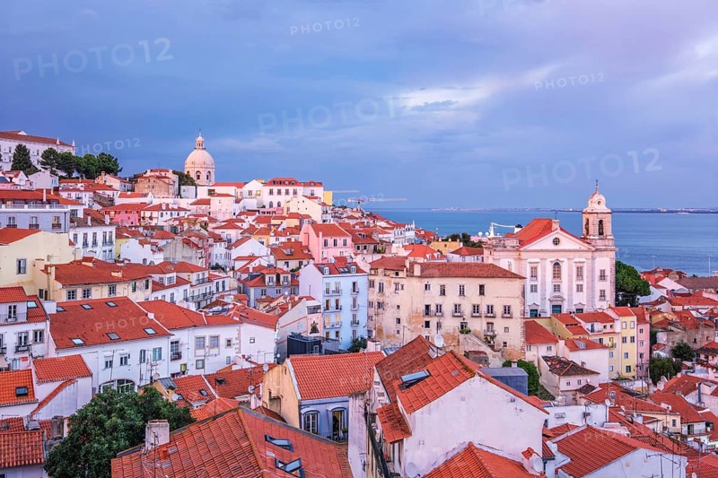 View of Lisbon famous view from Miradouro de Santa Luzia tourist viewpoint over Alfama old city district on sunset with dramatic overcast sky. Lisbon