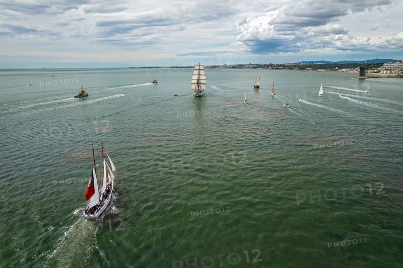 Aerial drone view of tall ships with sails sailing in Tagus river towards the Atlantic ocean in Lisbon