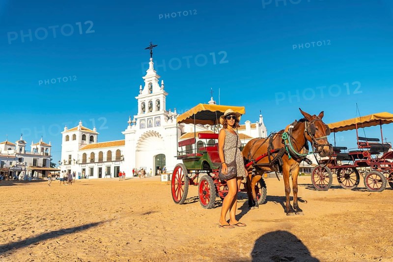 A tourist next to horses and carriages in the Rocio sanctuary in the festival of El Rocio in summer