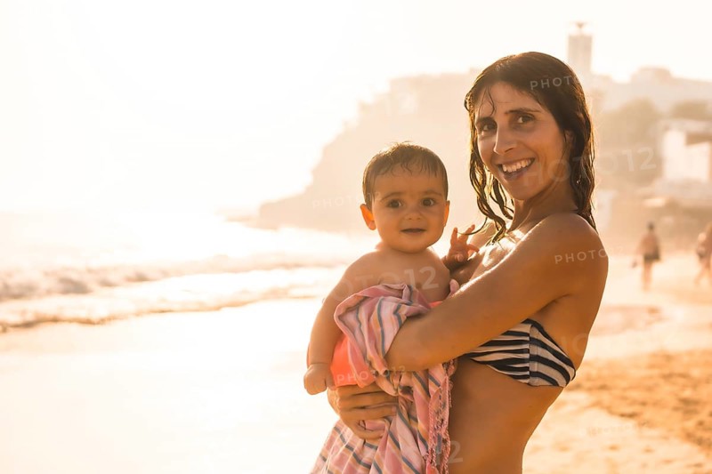 A mother with her baby enjoying a sunset on a beach