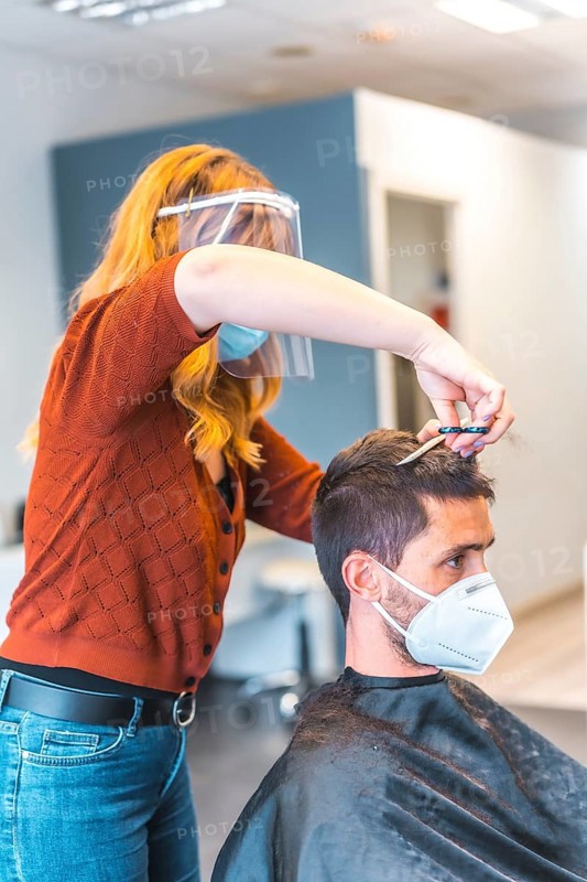 Hairdressers after the Coronavirus pandemic. Hairdresser with face mask and protective screen