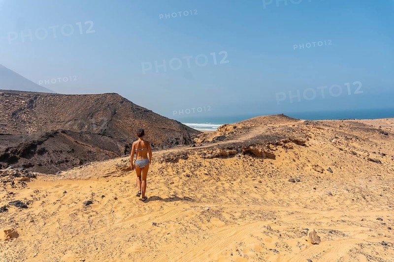 A young woman on a path of the wild beach Cofete of the natural park of Jandia
