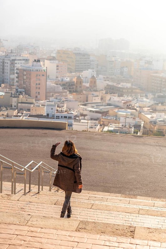 A young tourist on the stairs of the viewpoint of Cerro San Cristobal and the city of Almeria in the background