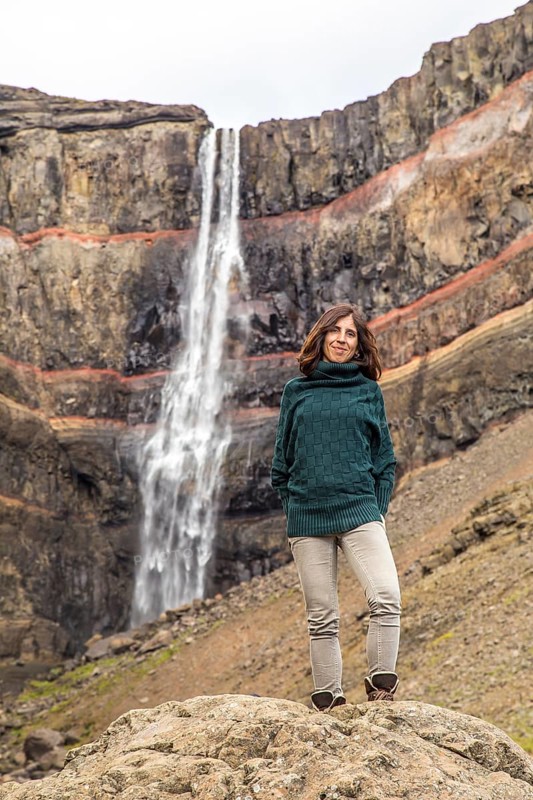 A young woman looking at the waterfall above Hengifoss from above. Iceland