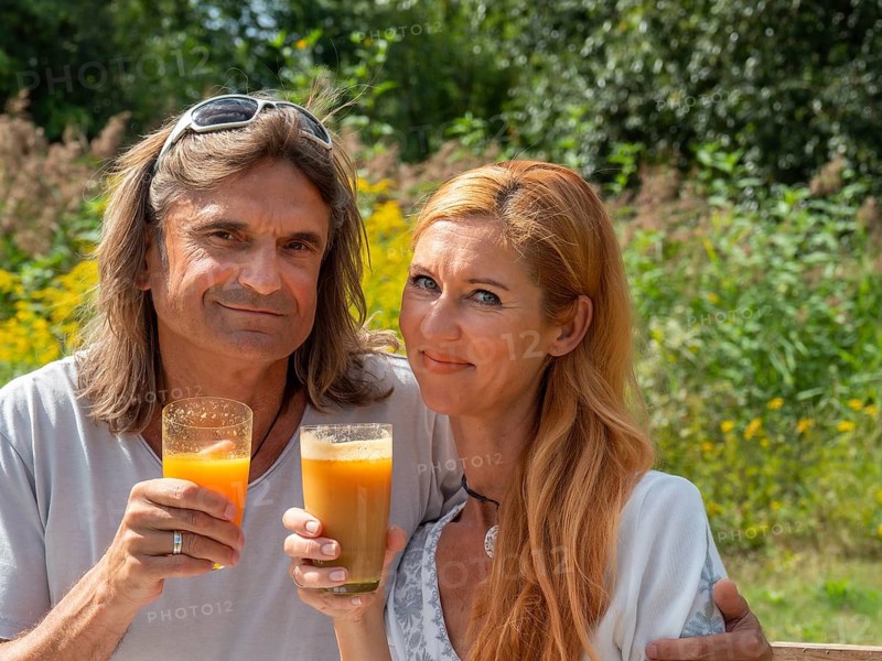 Man and woman in the garden with freshly squeezed fruit juice
