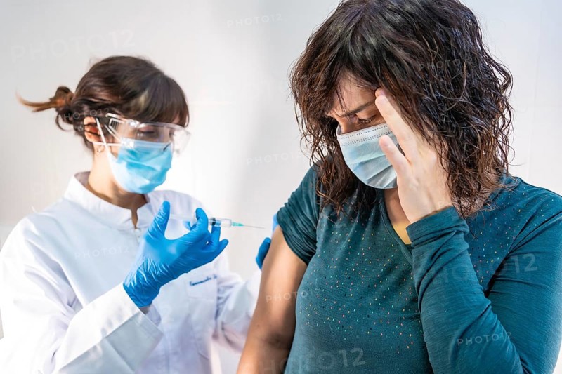 A woman doctor with a face mask applying the coronavirus vaccine