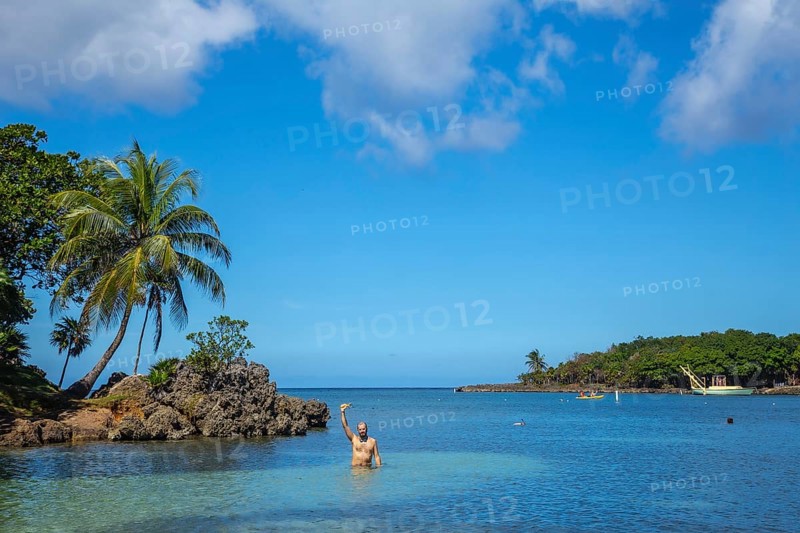 A young man entering the Caribbean Sea at West End Beach on Roatan Island. Honduras