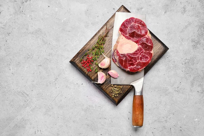 Top view of raw beef shank cross-cut on cleaver with spice and herb