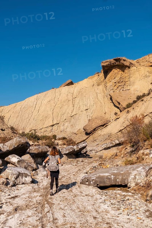 A young hiker with backpack and straw hat in the desert of Tabernas