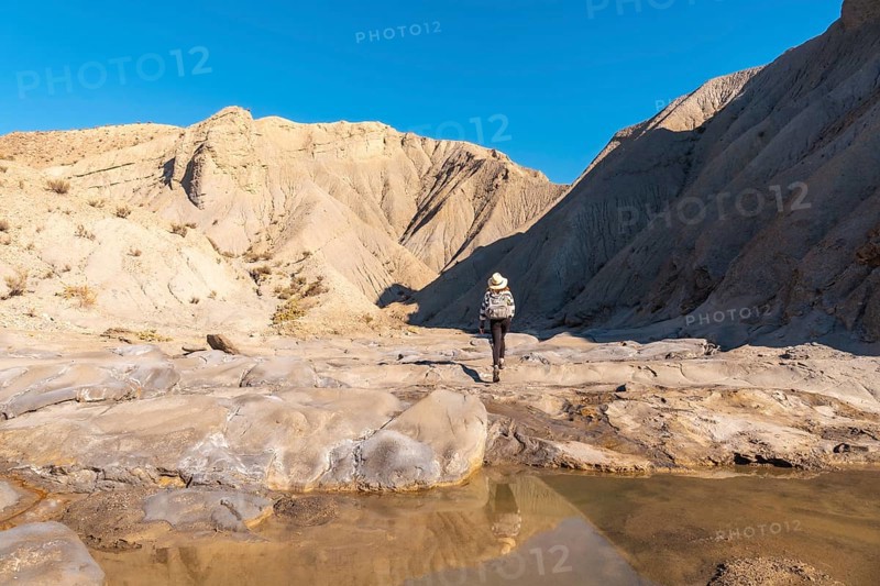 A young woman walking along the water in the desert on a trek in the Travertino waterfall and Rambla de Otero in the desert of Tabernas