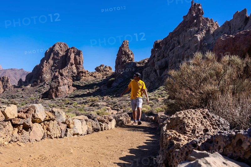 A tourist walking next to the Roques de Gracia and the Roque Cinchado in the natural area of Teide in Tenerife