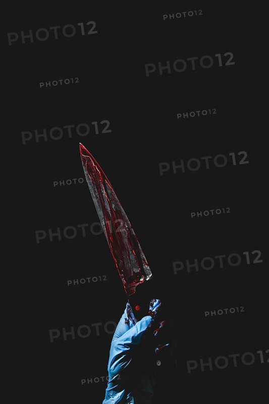 Upward pointing hand in blue glove holds bloodstained knife