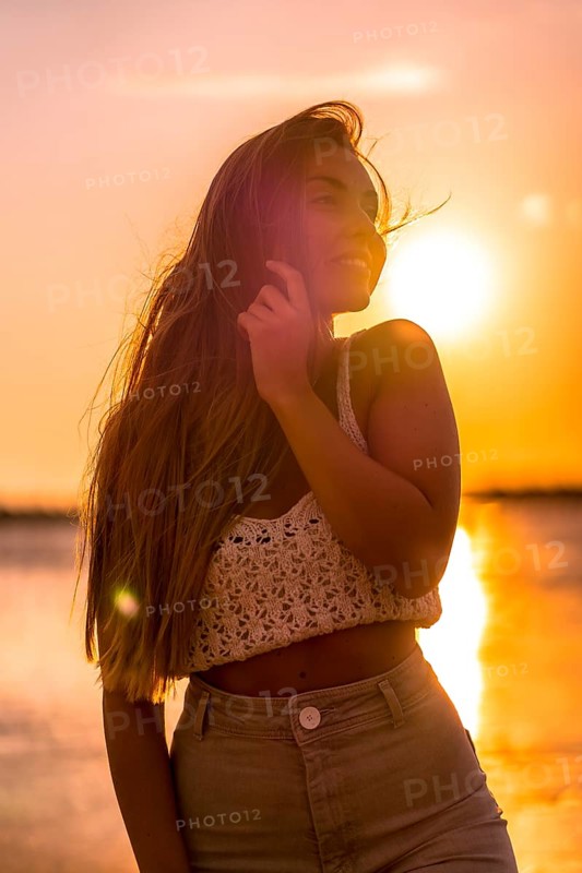 Summer lifestyle. A young blonde Caucasian woman in a white short wool sweater on a beach sunset