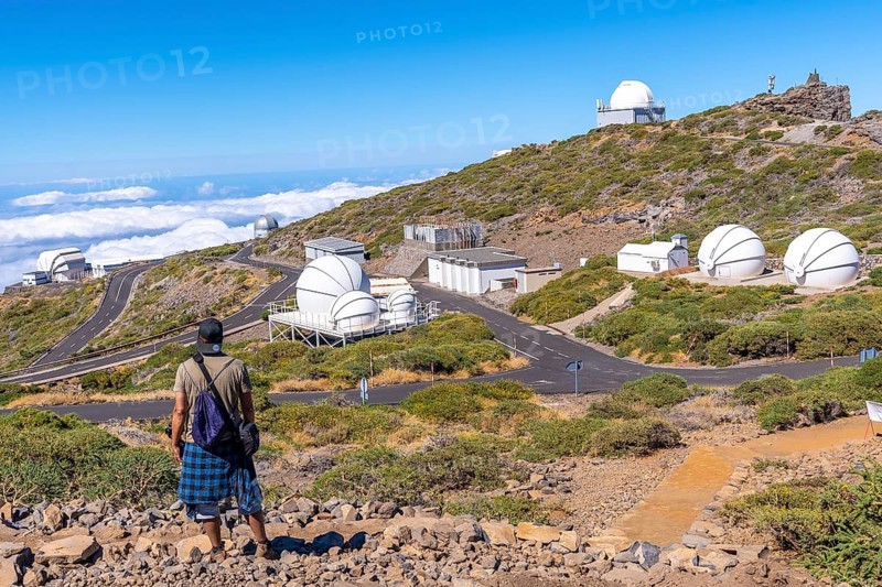 A young man on the trail looking at the telescopes of the Roque de los Muchachos national park on top of the Caldera de Taburiente