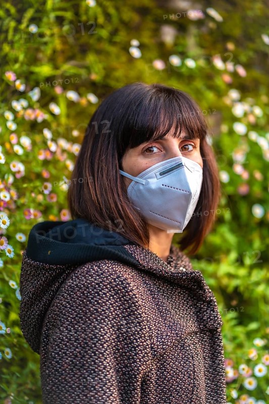A young woman with a mask on her first walks in mistrust. First walks of the uncontrolled Covid-19 pandemic