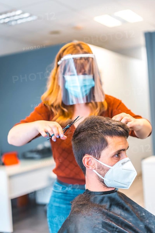 Hairdressers after the Coronavirus pandemic. Caucasian hairdresser with face mask and protective screen