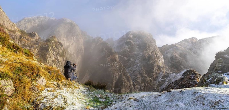 Panoramic of a photographer taking a photo with the tripod in the snowy winter sunset
