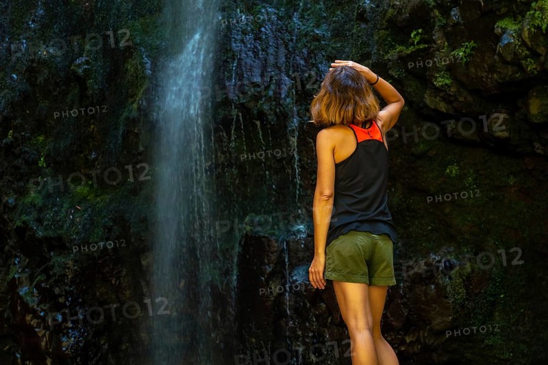An unrecognizable young woman at the waterfall at the Levada do Caldeirao Verde