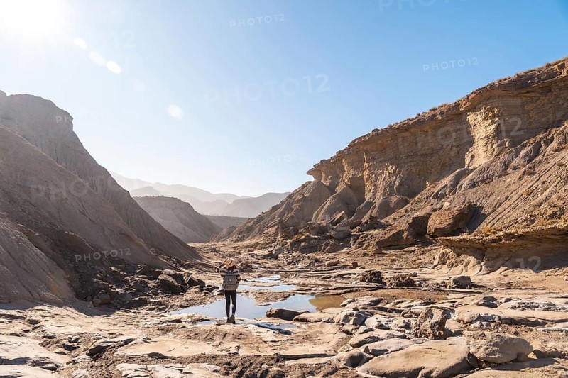 A young woman walking along the water in the desert on a trek in the Travertino waterfall and Rambla de Otero in the desert of Tabernas