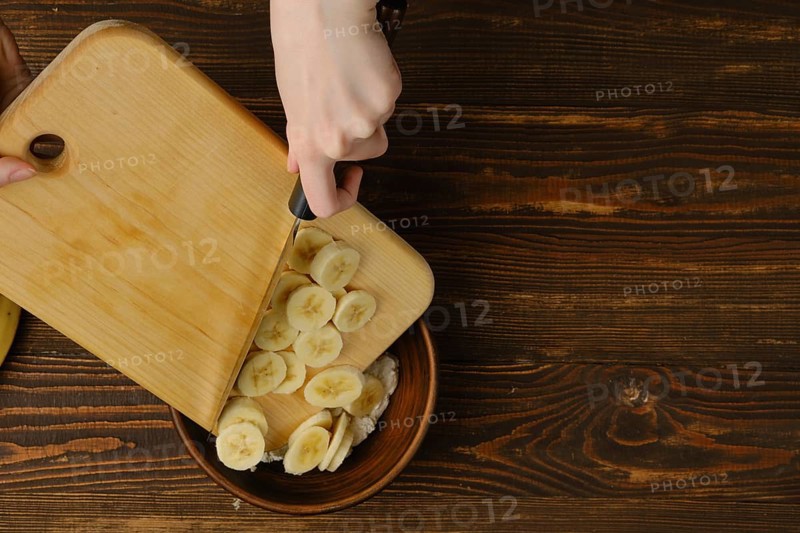 Dropping slices of banana into a bowl with cottage cheese
