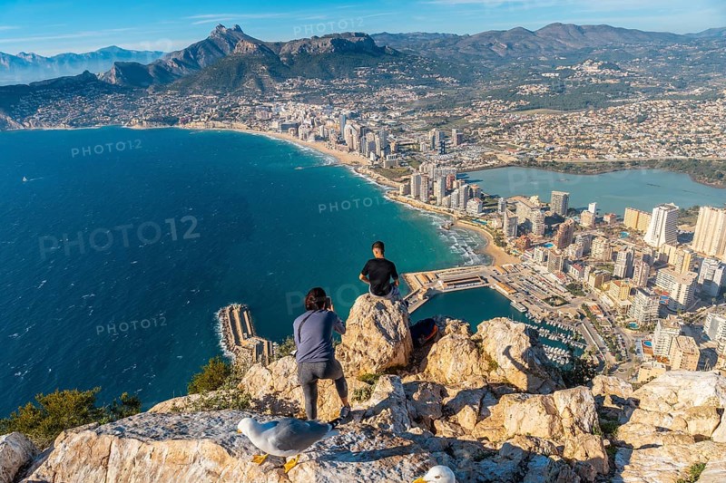A young man photographed sitting on top of the Penon de Ifach Natural Park in Calpe