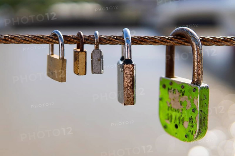 Old rusty padlocks hanging on bridge railing