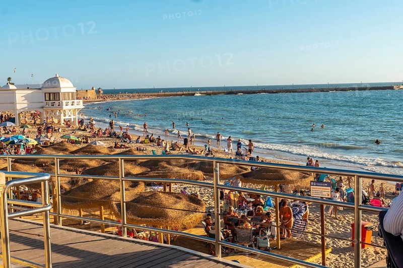 Bathers on the beach of La Caleta in the summer sunset of the city of Cadiz. Andalusia