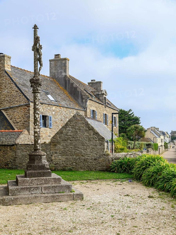 Calvaire in front of the church Eglise Notre-Dame-du-Bon-Secours and stone house