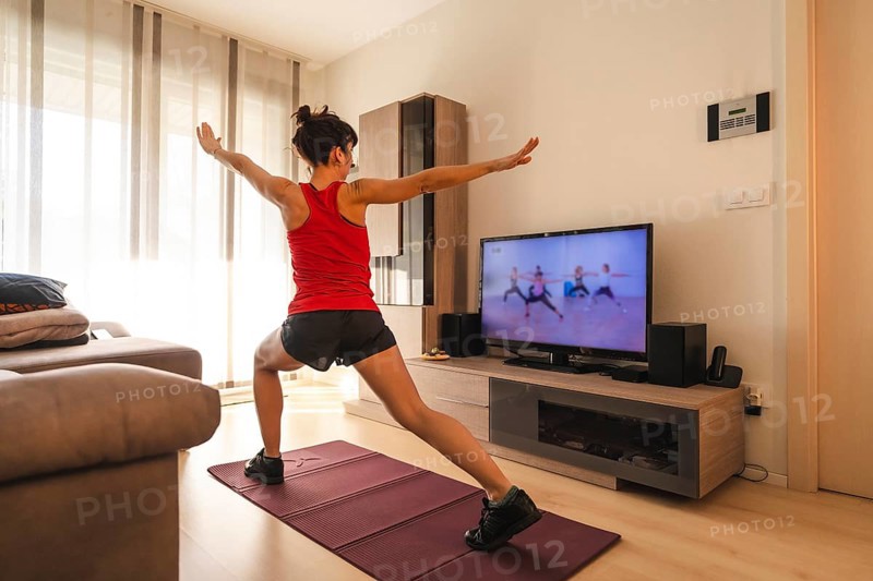 A young woman doing stretching in the room following the instructions of the online teacher. Sport in the covid19 quarantine at home