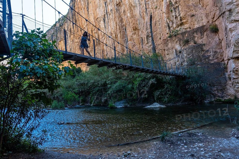 A young girl crossing the wooden suspension bridges. Ruta de los Pantaneros in the town of Chulilla in the Valencian community. Spain