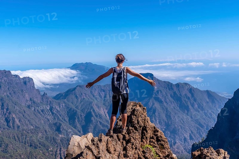 A young woman looking out from the top of the Caldera de Taburiente volcano near Roque de los Muchachos one summer afternoon