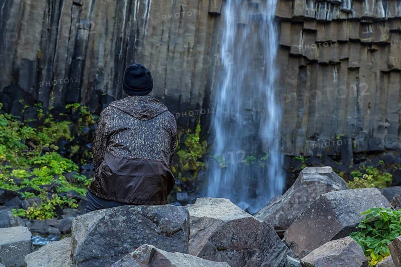 A man in Svartifoss waterfall