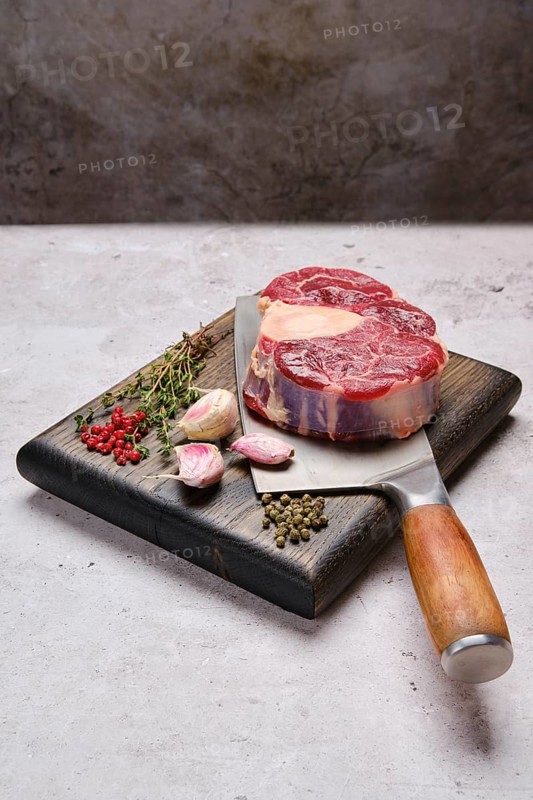 Big piece of raw beef shank cross-cut on cleaver with spice and herb