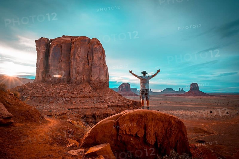 A boy in a white T-shirt in the sunset inside Monument Valley National Park. Utah