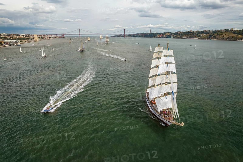 Aerial drone view of tall ships with sails sailing in Tagus river towards the Atlantic ocean in Lisbon