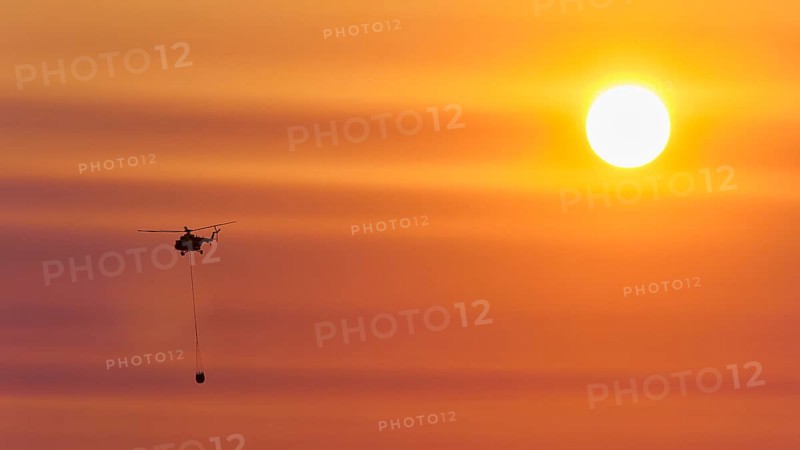 Firefighting helicopter in sunset